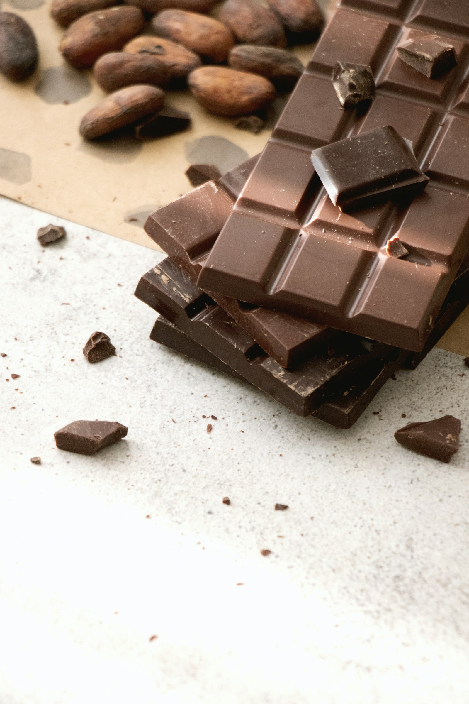 A stack of dark chocolate bars with cocoa beans on craft paper